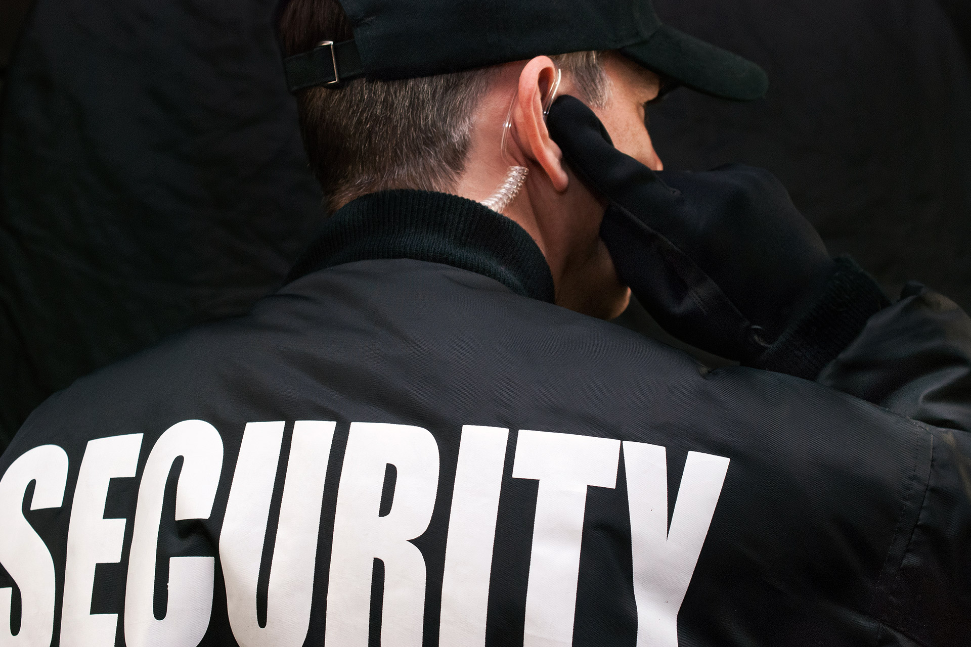 back of a security guard in uniform listening on an earpiece